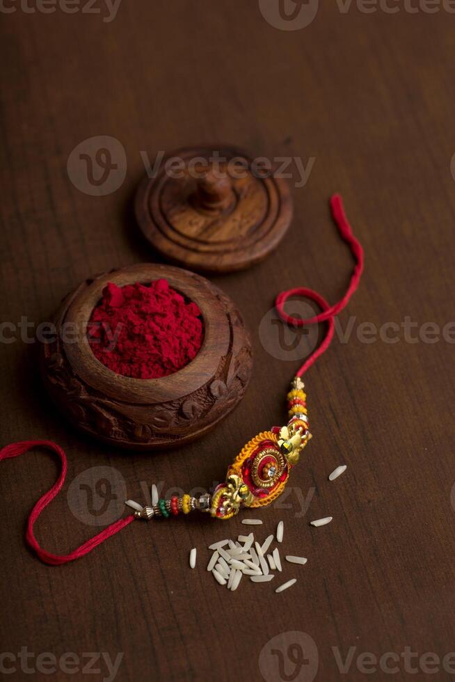 Indian festival Raksha Bandhan background with an elegant Rakhi, Rice Grains and Kumkum. A traditional Indian wrist band which is a symbol of love between Brothers and Sisters. photo
