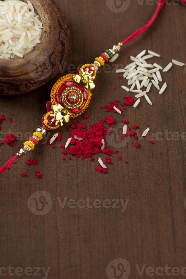 Indian festival Raksha Bandhan background with an elegant Rakhi, Rice Grains and Kumkum. A traditional Indian wrist band which is a symbol of love between Brothers and Sisters. photo