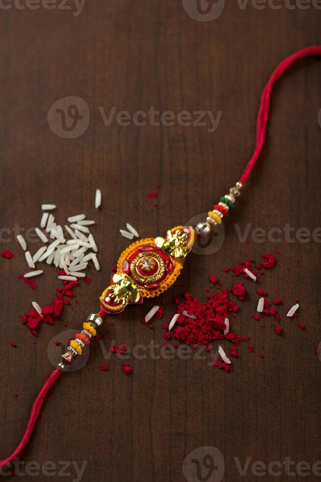Indian festival Raksha Bandhan background with an elegant Rakhi, Rice Grains and Kumkum. A traditional Indian wrist band which is a symbol of love between Brothers and Sisters. photo