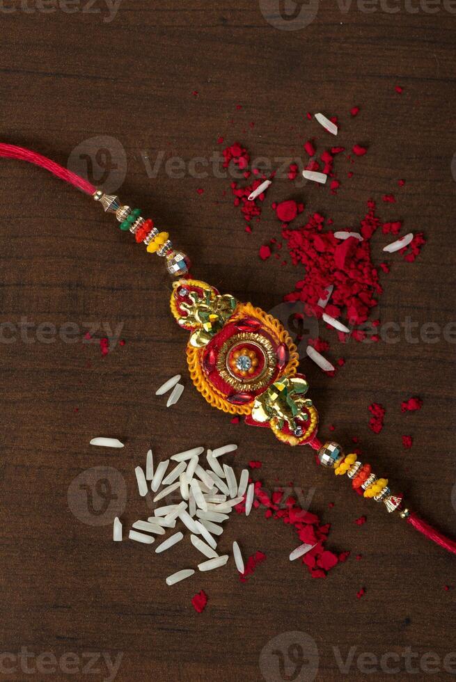 Indian festival Raksha Bandhan background with an elegant Rakhi, Rice Grains and Kumkum. A traditional Indian wrist band which is a symbol of love between Brothers and Sisters. photo