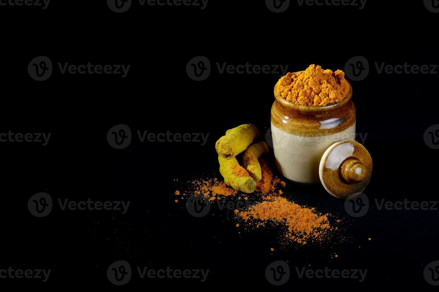 A jar of tumeric and a spoon of tumeric photo