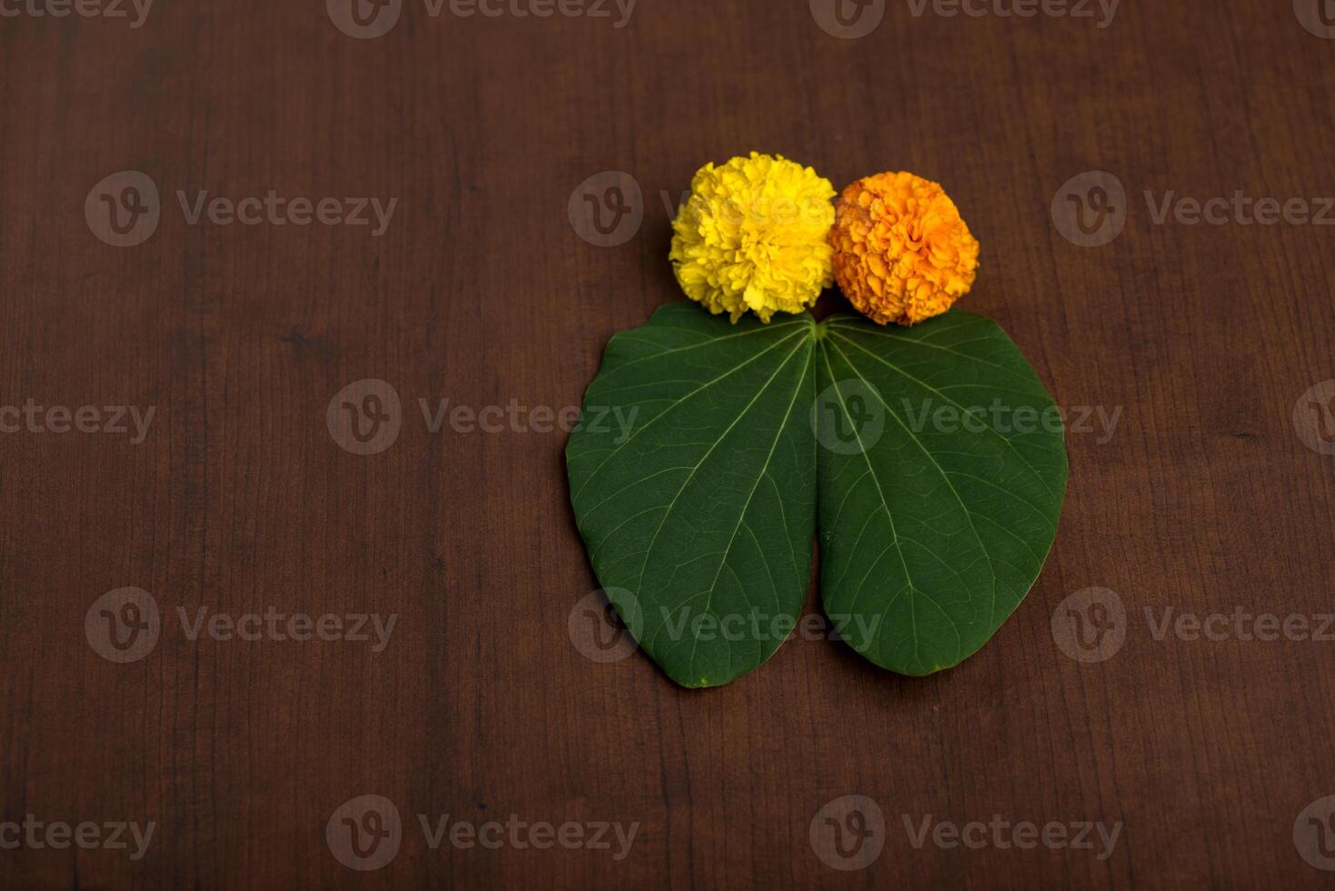 A yellow flower and green leaf on a brown table photo