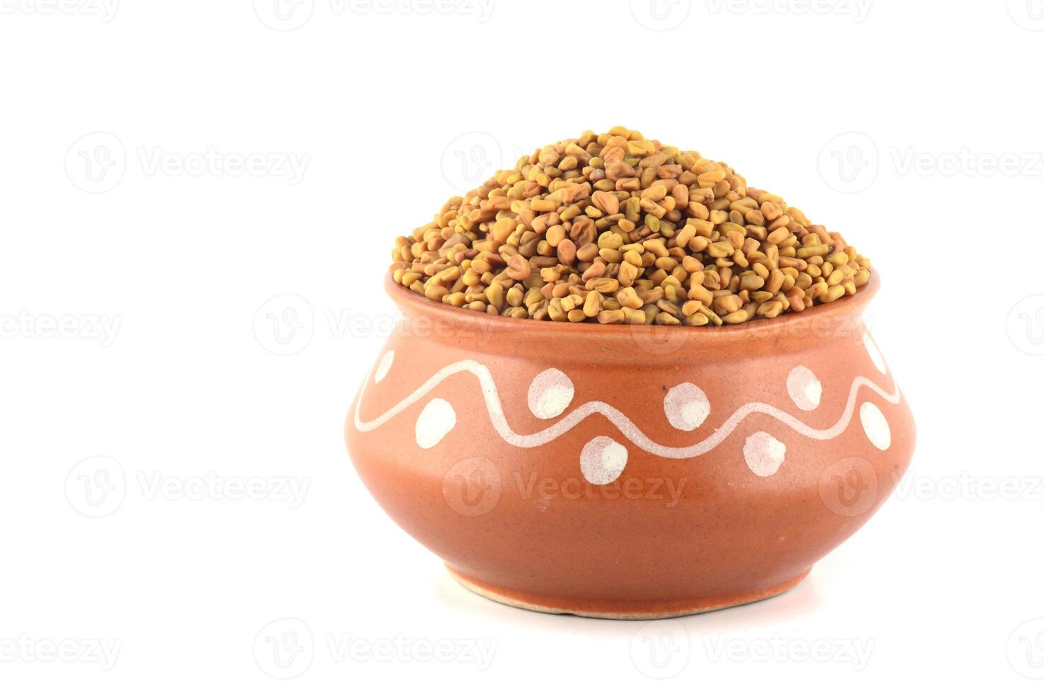 Fenugreek seeds in clay pot isolated on white background photo