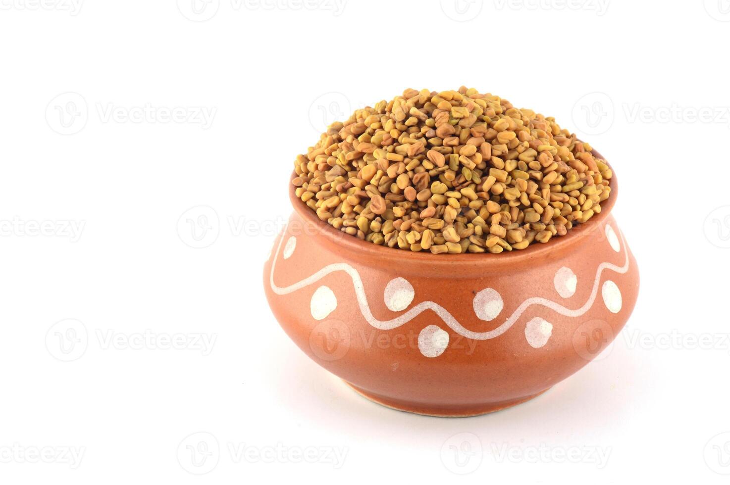 Fenugreek seeds in clay pot isolated on white background photo