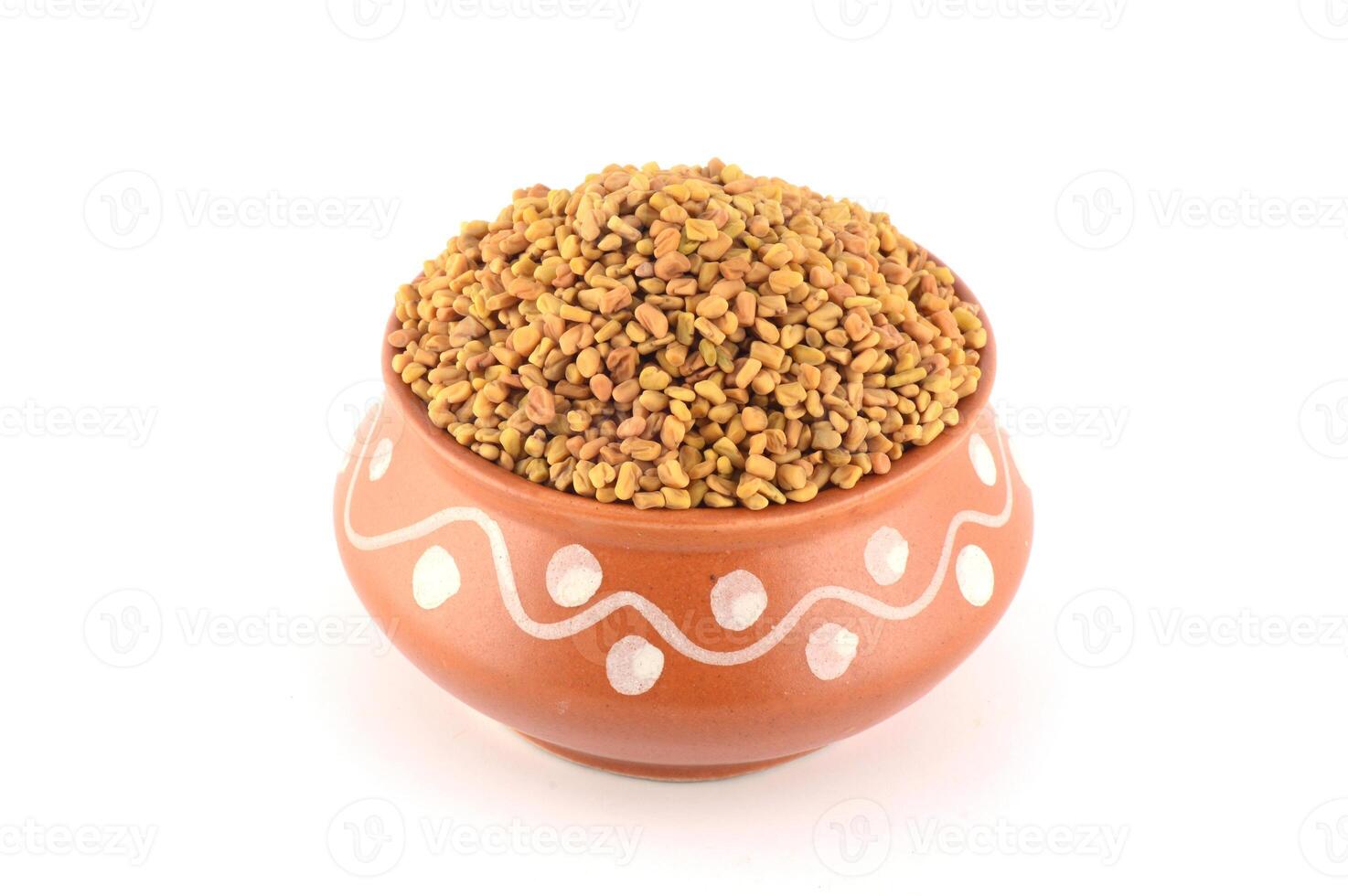 Fenugreek seeds in clay pot isolated on white background photo