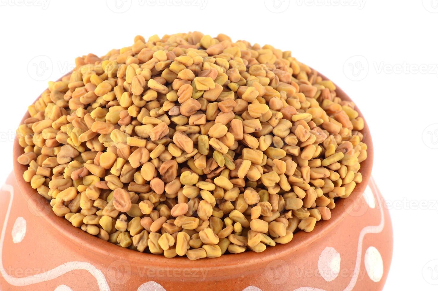 Fenugreek seeds in clay pot isolated on white background photo