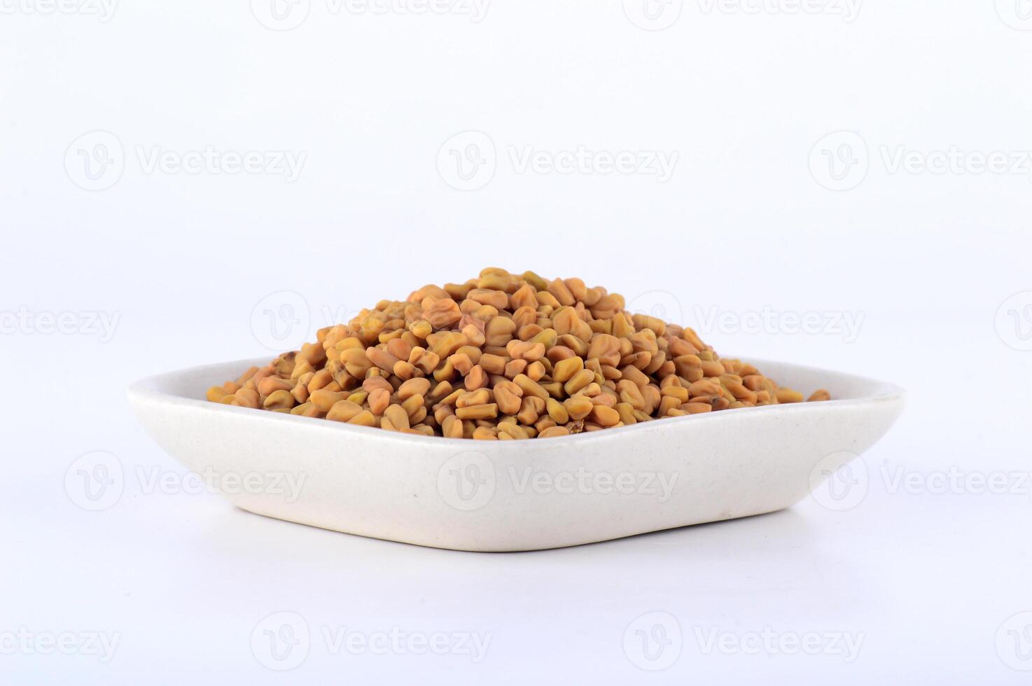Fenugreek seeds in white plate isolated on white background photo