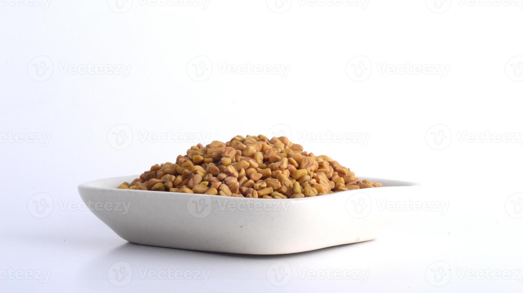 Fenugreek seeds in white plate isolated on white background photo