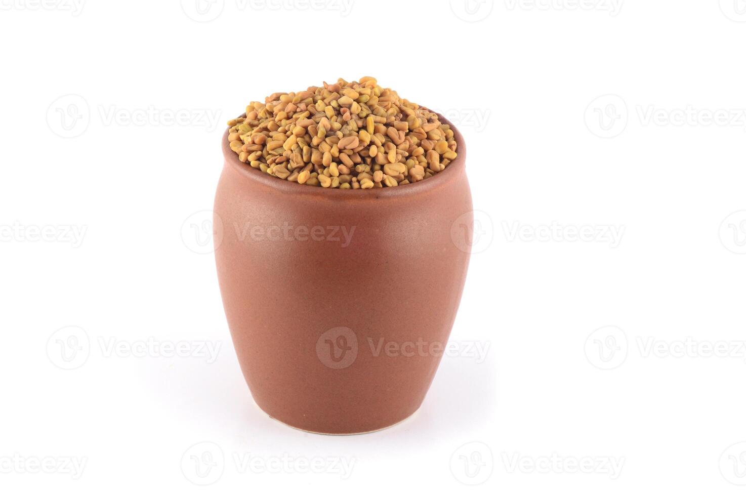Fenugreek seeds in clay pot isolated on white background photo