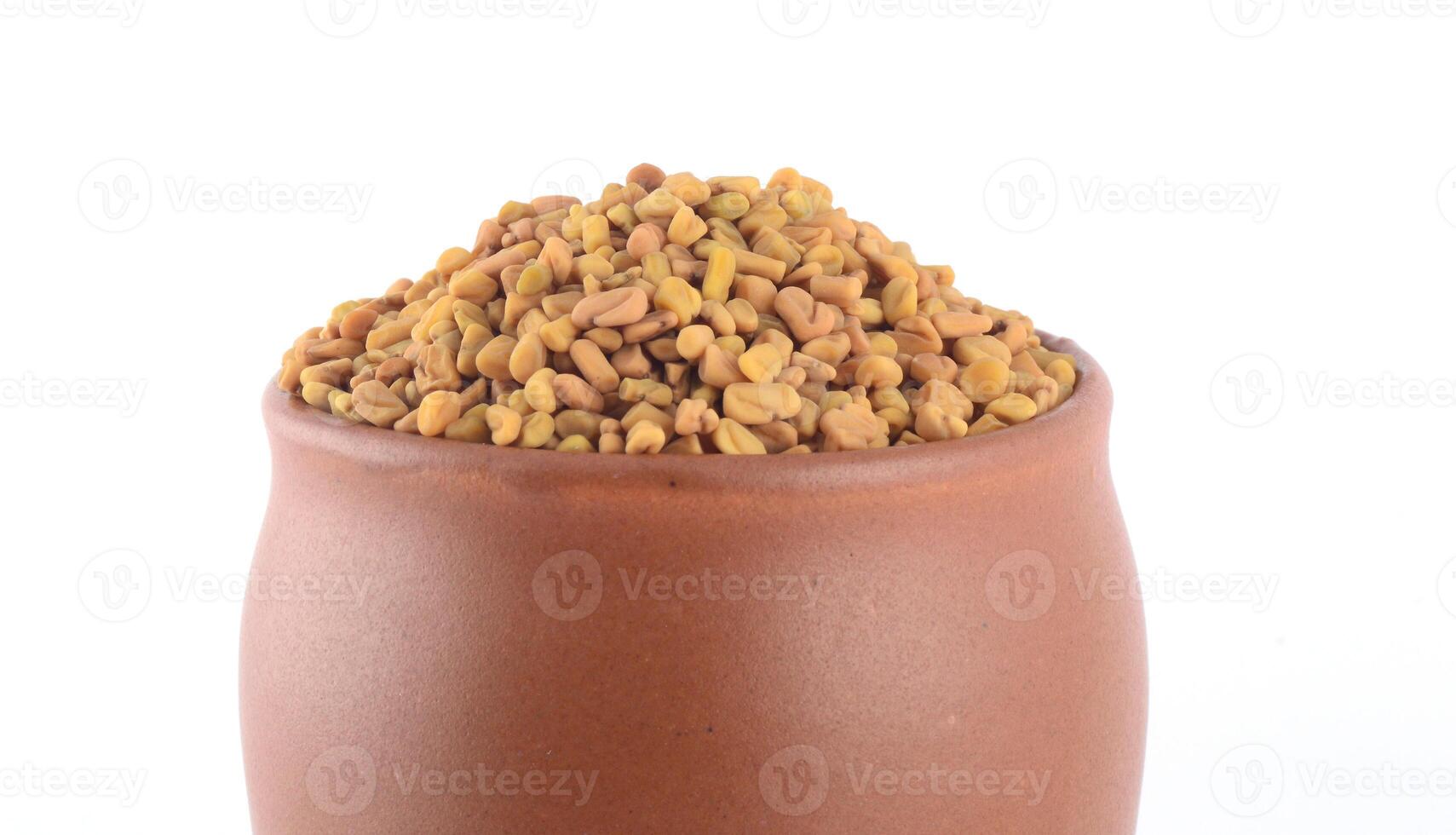 Fenugreek seeds in clay pot isolated on white background photo