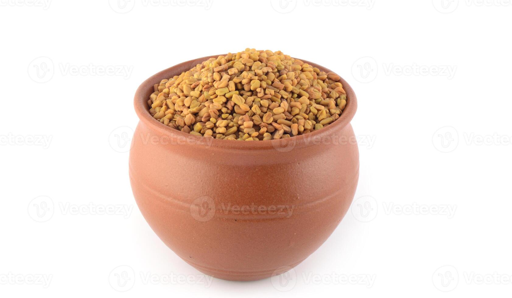 Fenugreek seeds in clay pot isolated on white background photo