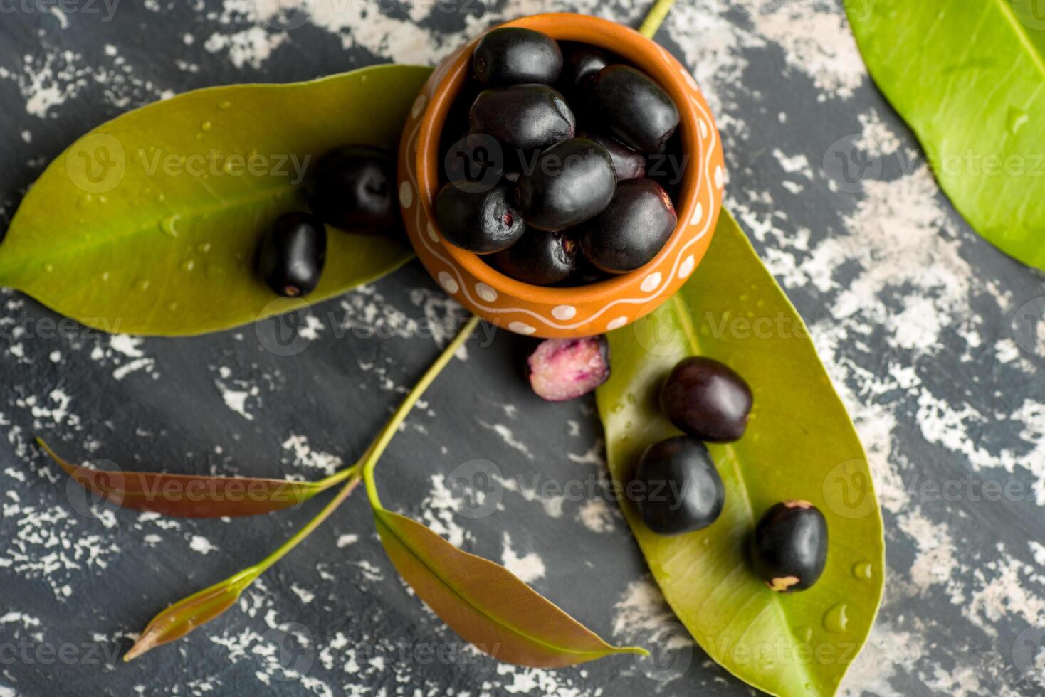 Jambolan plum or jambul or Jamun fruit, Java plum Syzygium cumini with leaf on stone textured background. photo