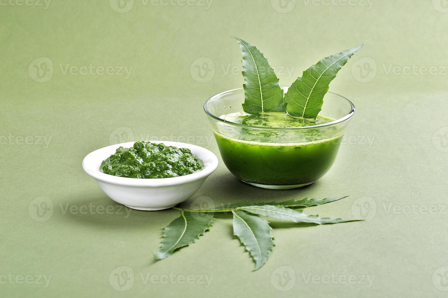 A bowl of green juice and a leaf on a green background photo