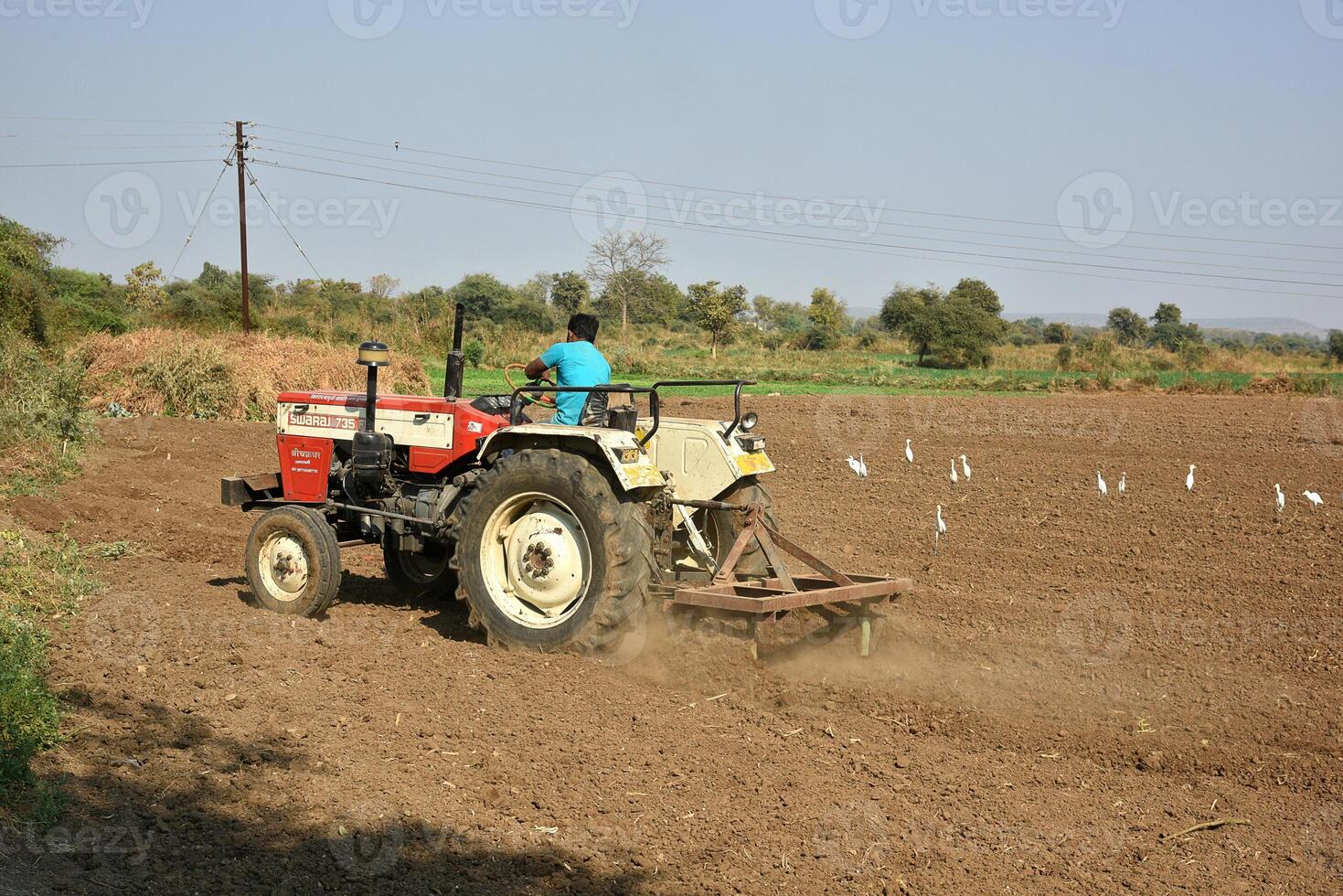 A man is driving a tractor on a field photo