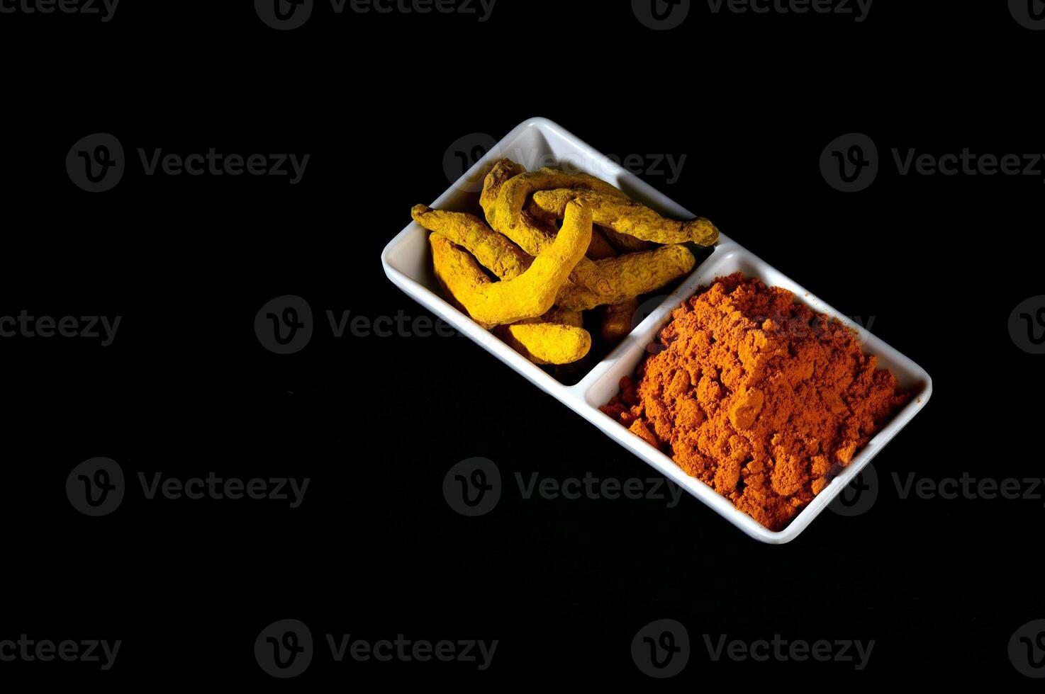 Dry Turmeric powder and roots or barks in white plate photo
