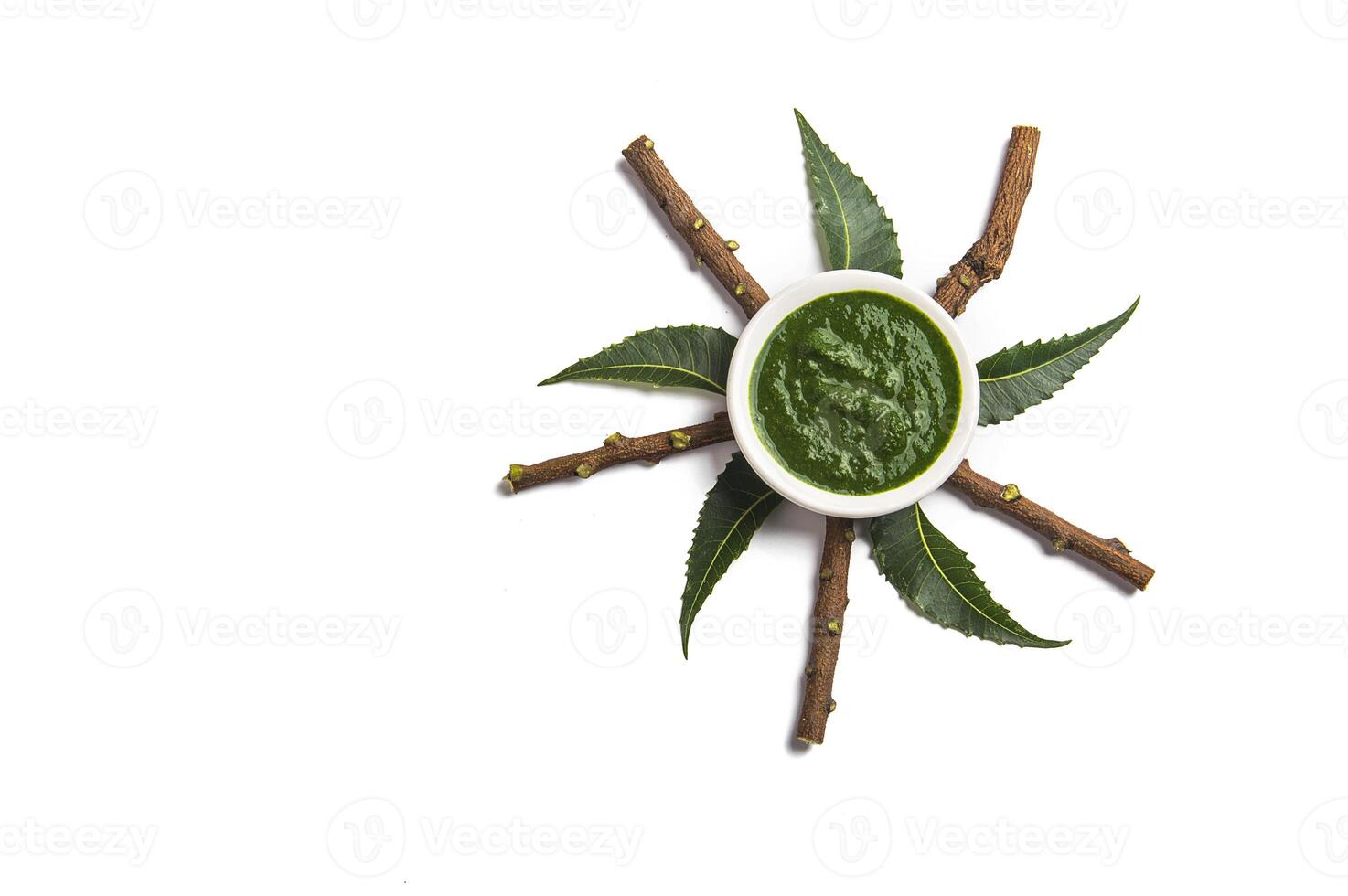 Medicinal Neem leaves with paste in bowl and twigs on white background photo