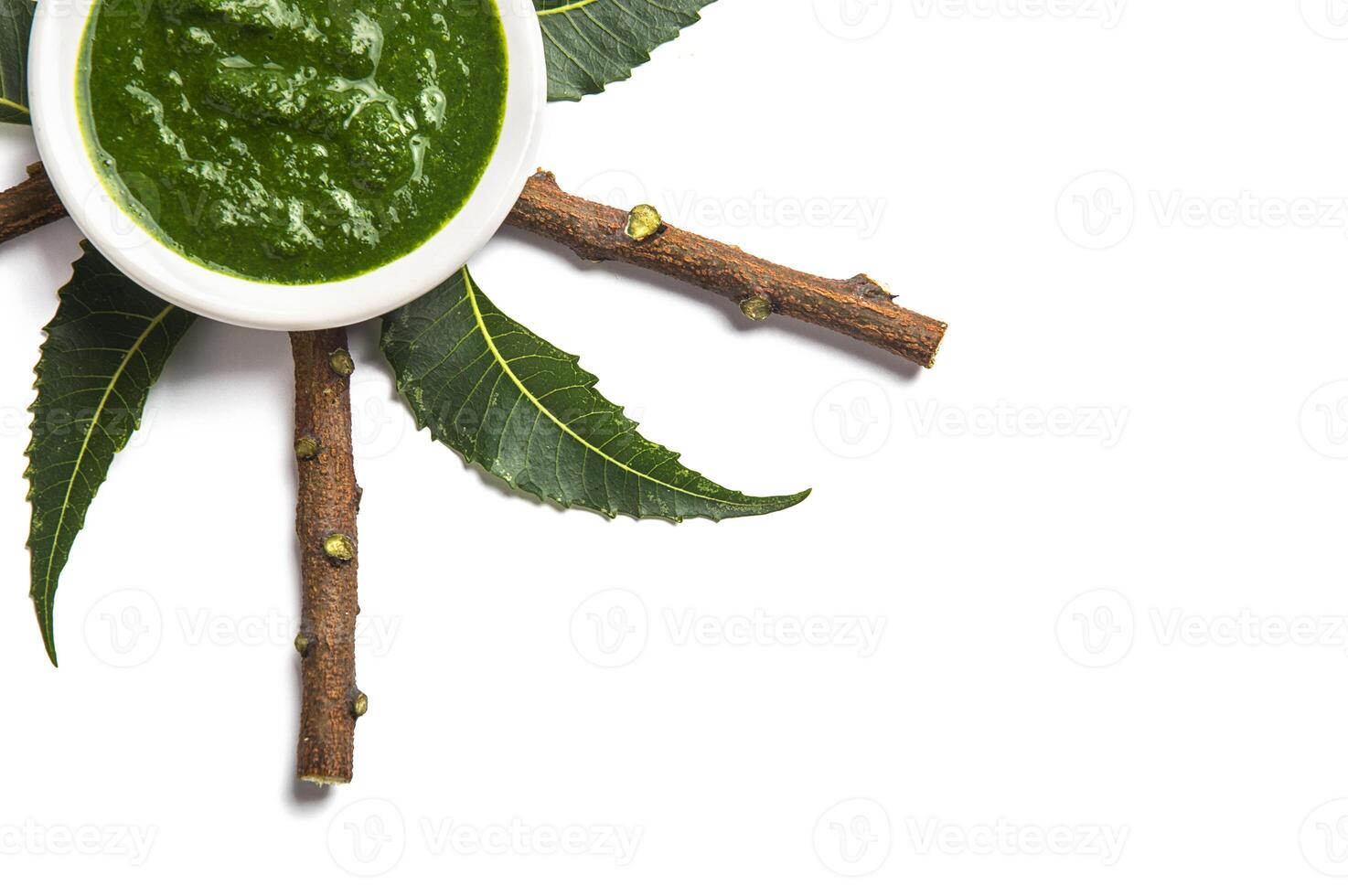 Medicinal Neem leaves with paste in bowl and twigs on white background photo