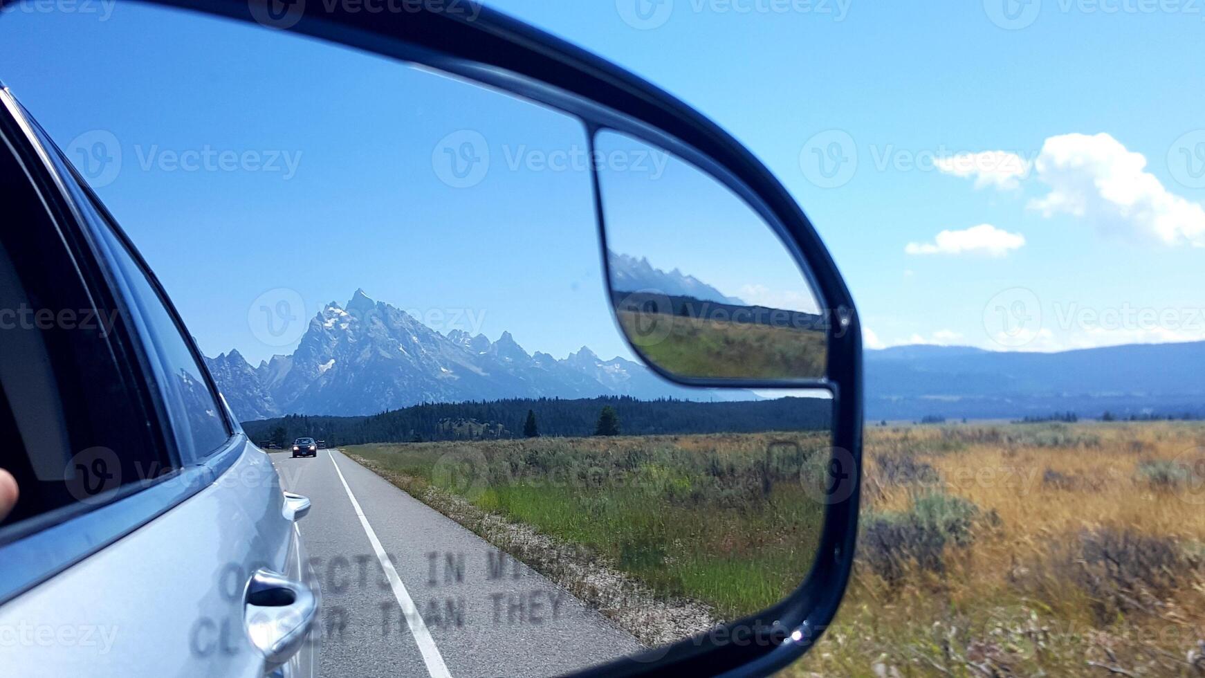 View of Mountains in Rear View Mirror of Silver Car, Summer Road Trip photo