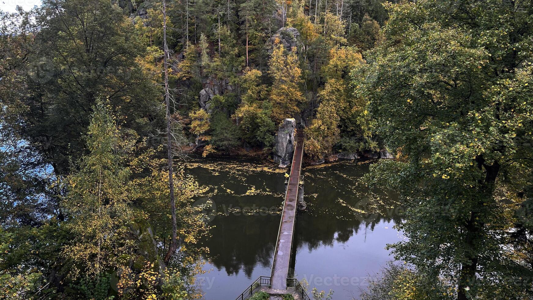 Pedestrian bridge across the Bobr River. Autumn landscape with colorful trees on the river bank. View from above. photo