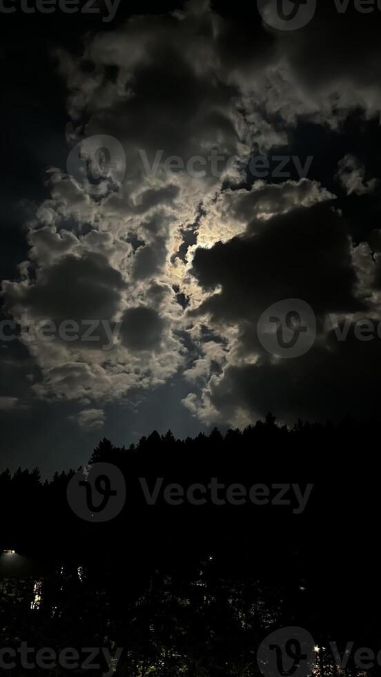 Night landscape, full moon behind clouds in the sky photo