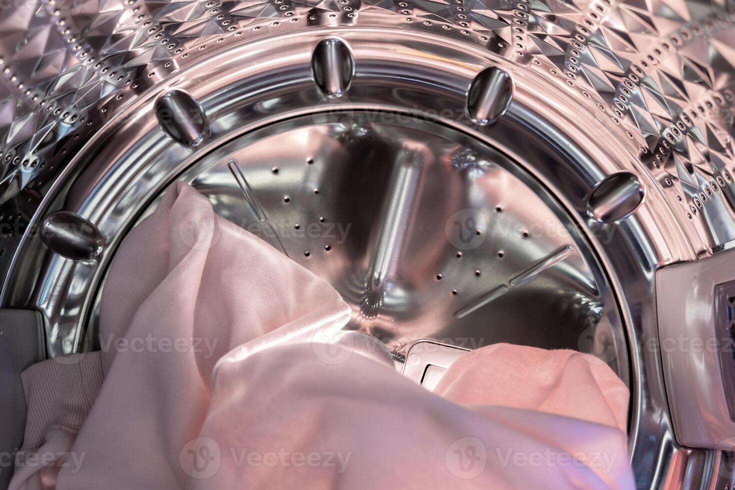 Close-up of clean pink linen clothes coming out of the washing machine after washing in the bathroom. Put the clothes in the washing machine to dry. photo