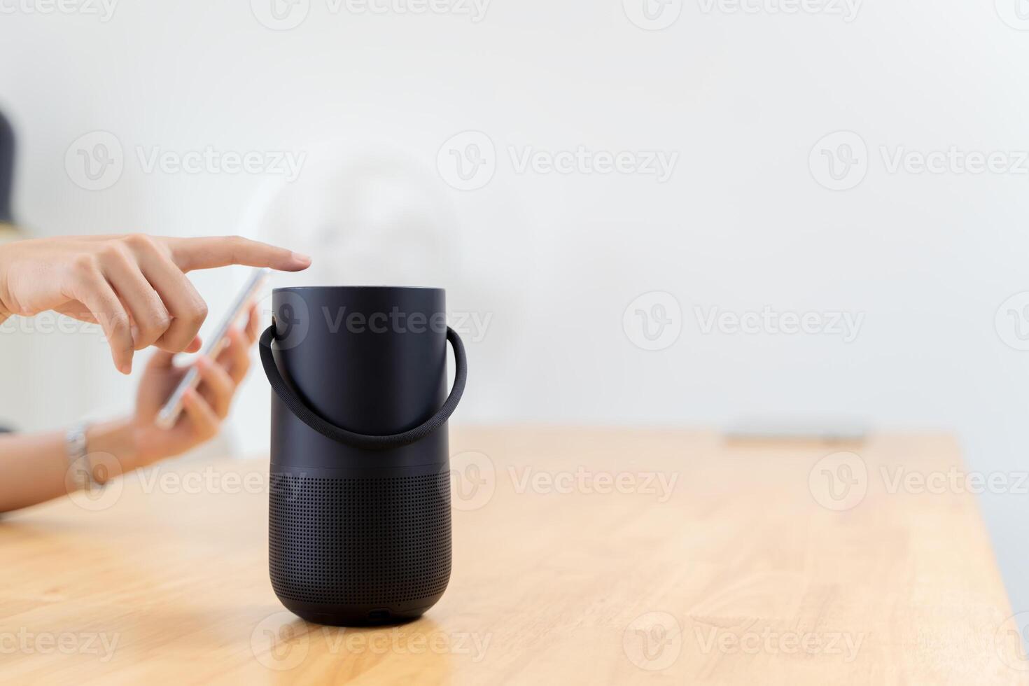 Close-up on hand using phone connecting portable speaker. Women connecting mobile phone to wireless portable speaker on table. photo