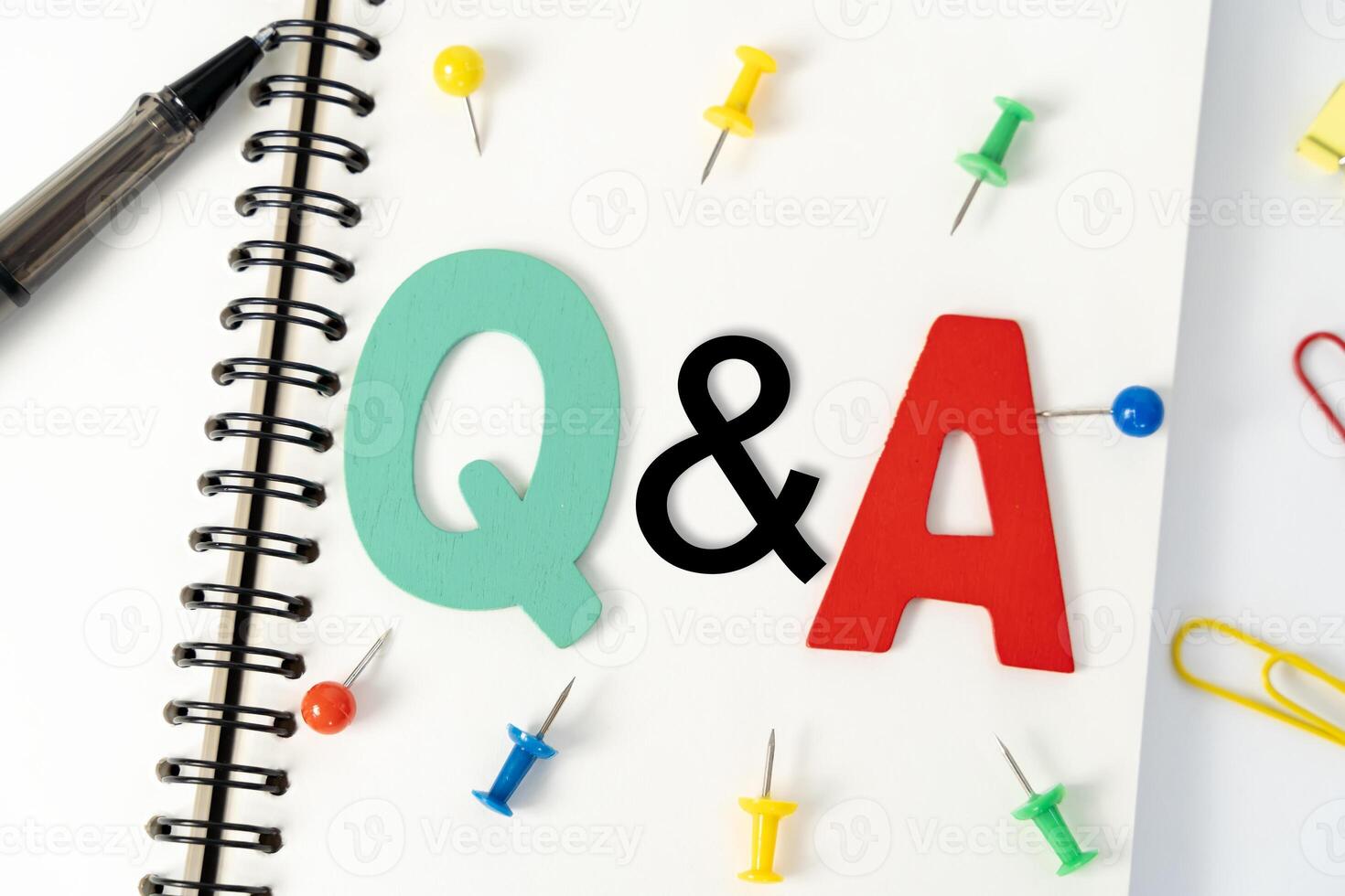 Blank multi-colored note paper with QA or questions and answers written on it. Top view of pen and glasses writing Q and A on desk. photo