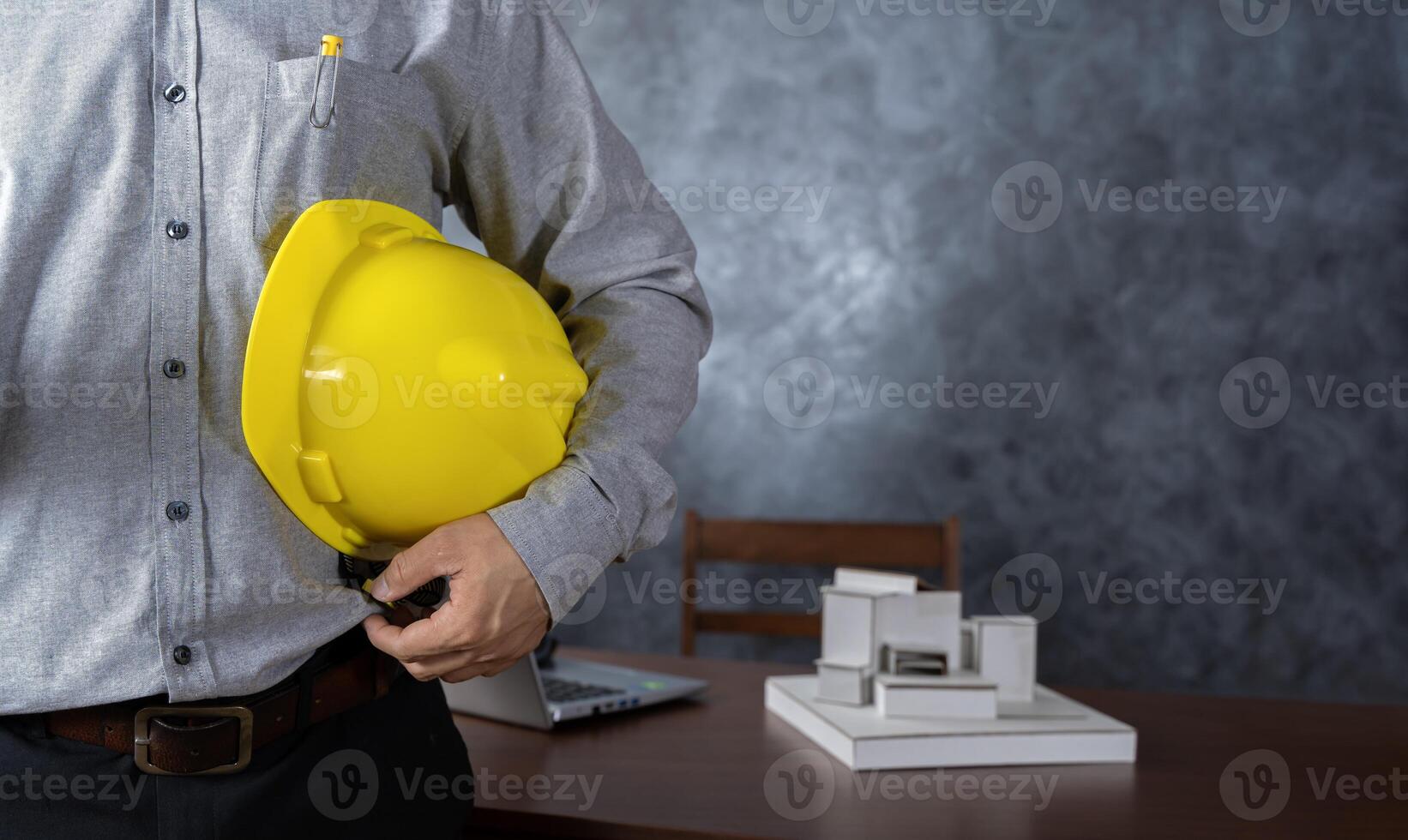Close-up of Engineer holding helmet checking accuracy of building structural blueprints from architect on the desk in office to proceed with the construction. photo