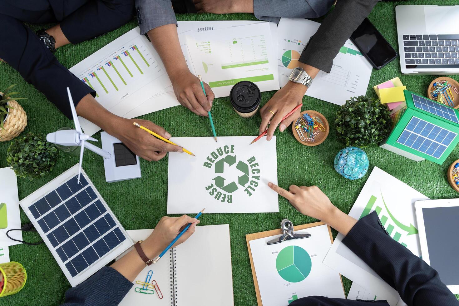Group of businessmen's hands touching green recycling symbol, showing a mockup of green earth with recycling icons. photo