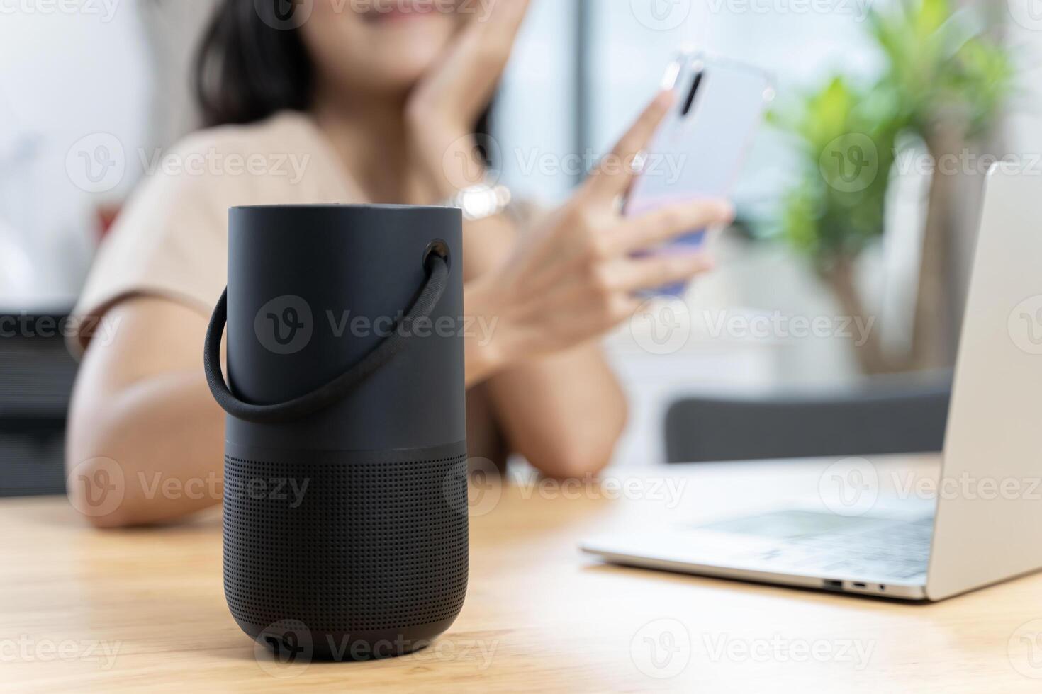 Close-up on hand using phone connecting portable speaker. Black Portable Wireless Bluetooth Speaker for Music. photo