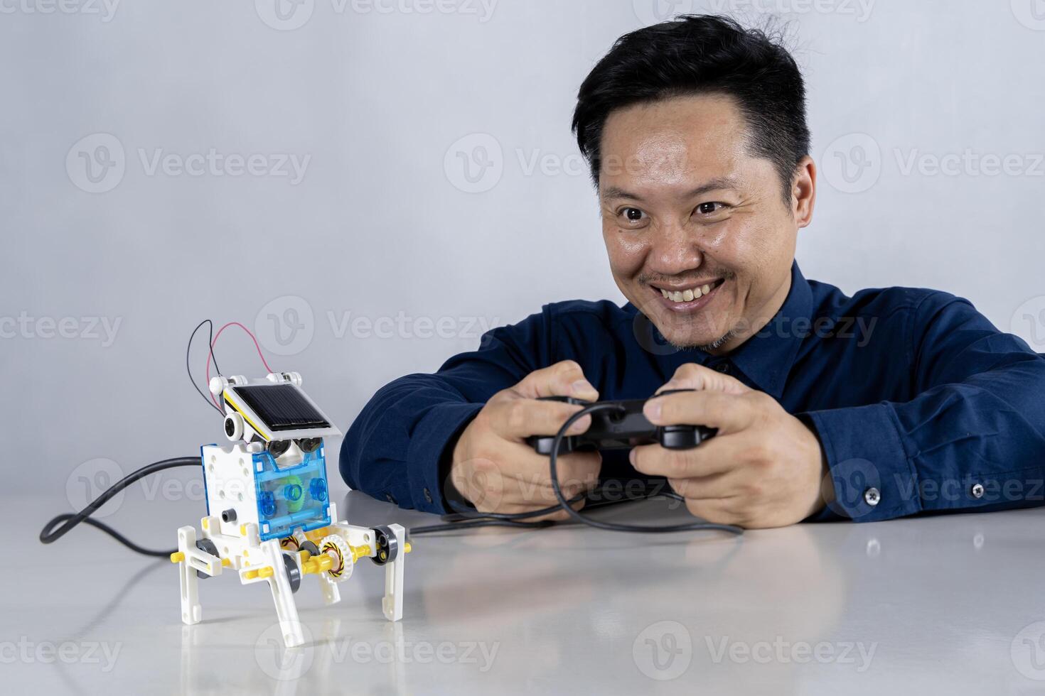 Asian man is building a robot project in his home. Robots control science lessons and coding, developing learning innovations. photo