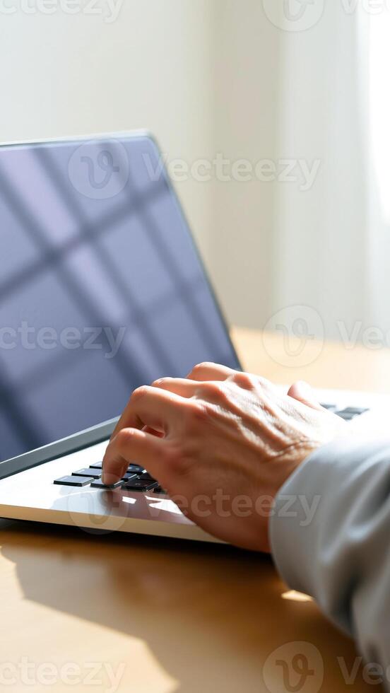 hand typing on a laptop with a window reflection photo