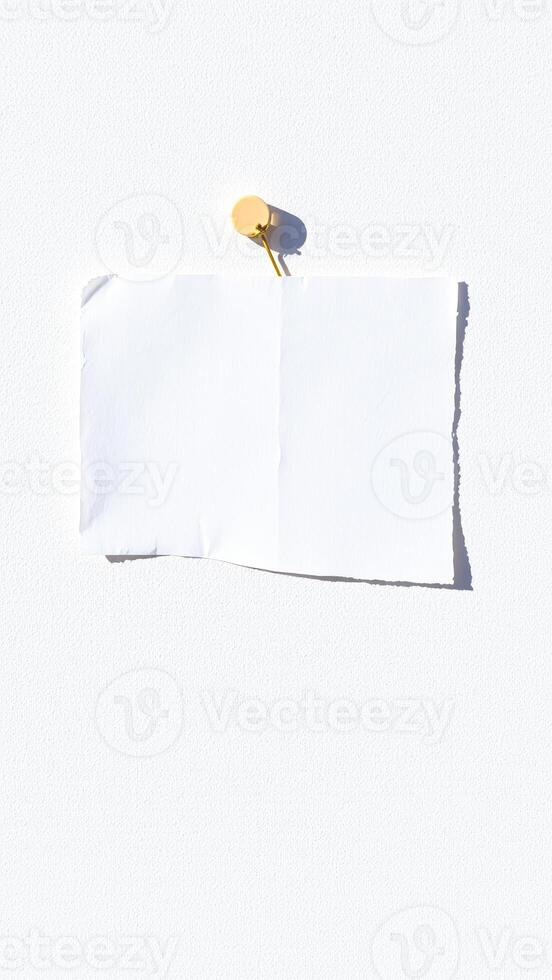 single sheet white paper attached a wall with a gold push pin photo