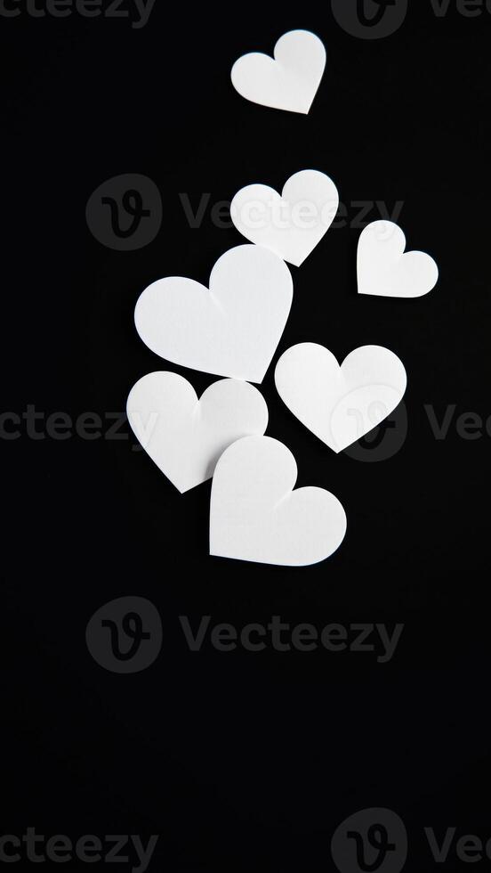 white paper hearts scattered on black photo