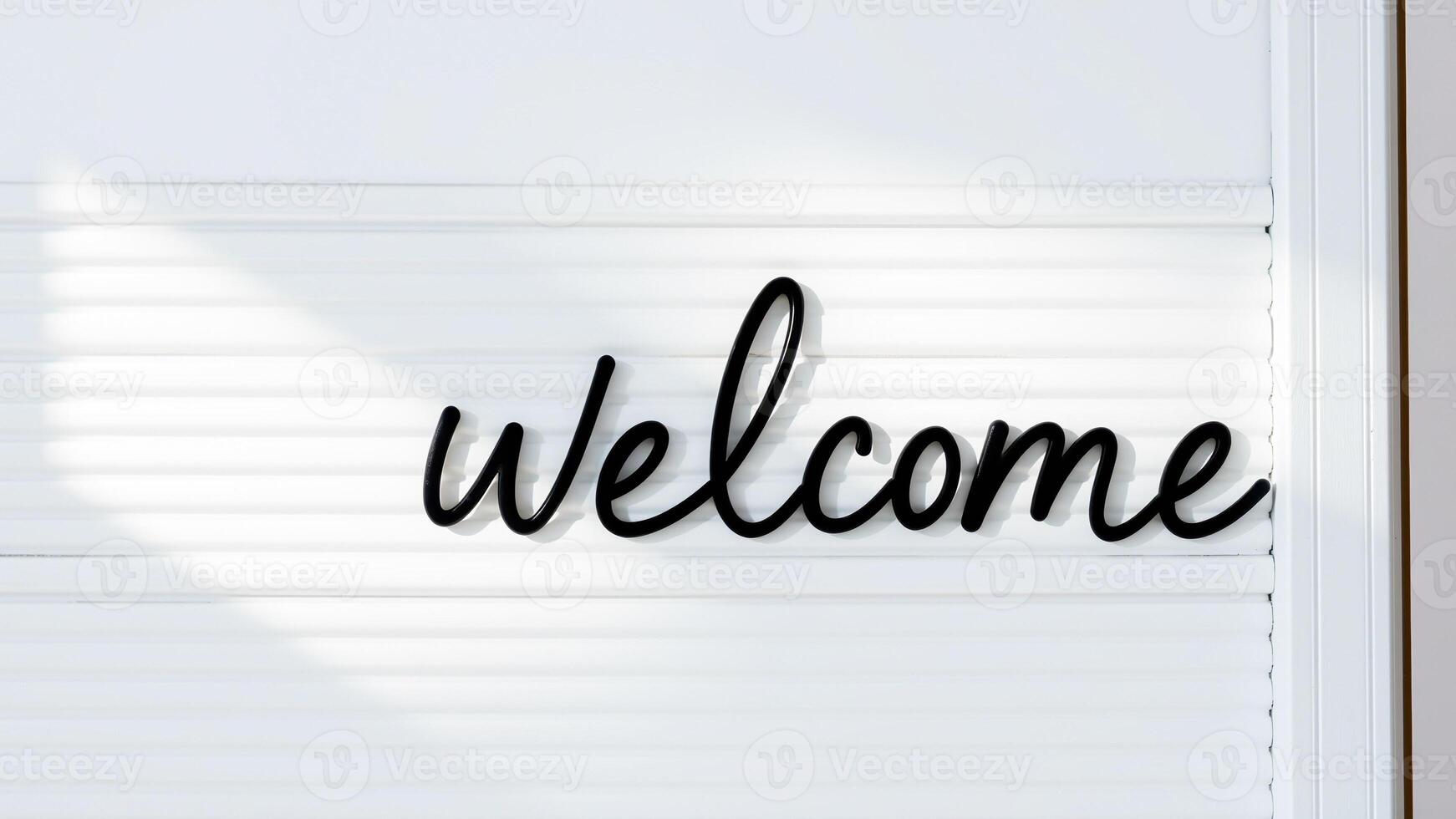 black cursive welcome sign on a white slatted surface photo