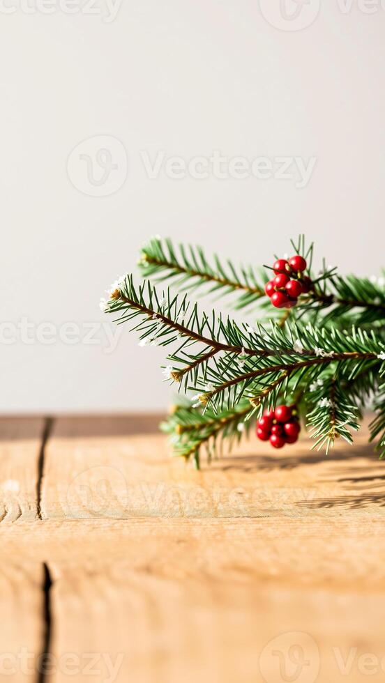 single pine branch with red berries resting on a wooden surface photo