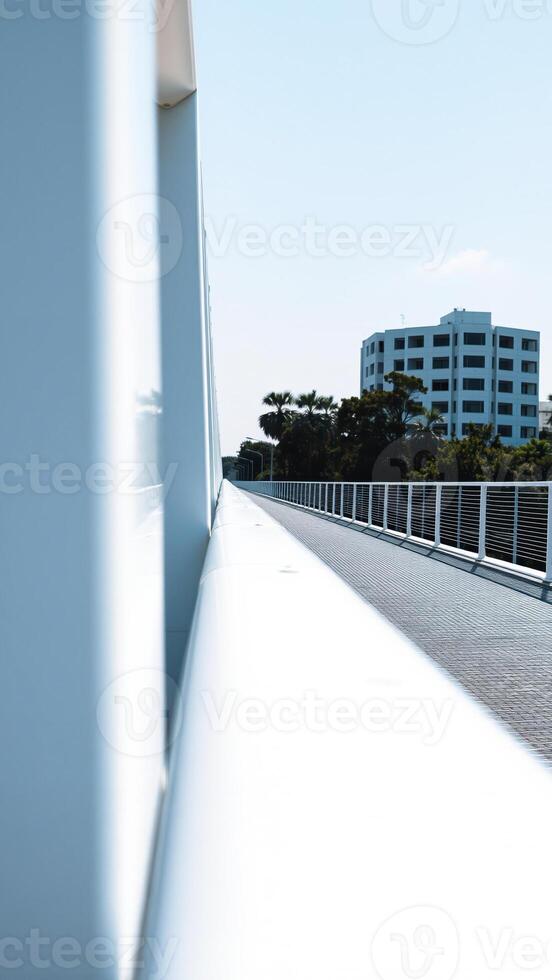 white pedestrian bridge leading towards a modern building. photo