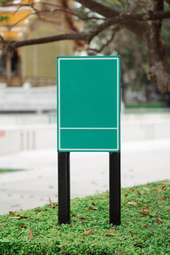 A blank green sign stands prominently in the park. photo