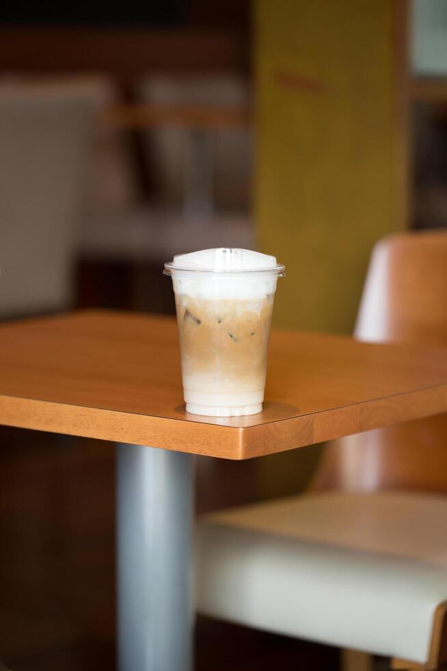 A refreshing Iced Cappuccino sits on a wooden table in a cozy cafe, inviting patrons to enjoy its creamy blend. photo