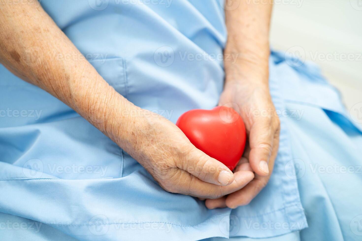 Asian elder senior woman patient holding red heart in hospital. photo