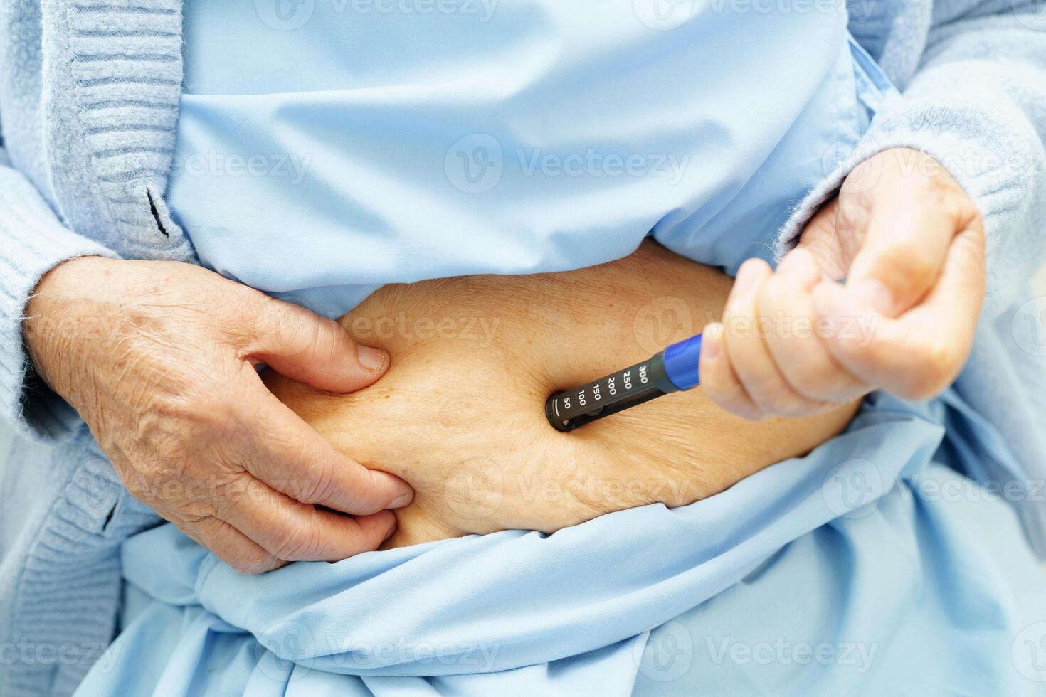 Asian senior woman making injection insulin pen in belly to treatment diabetes. photo