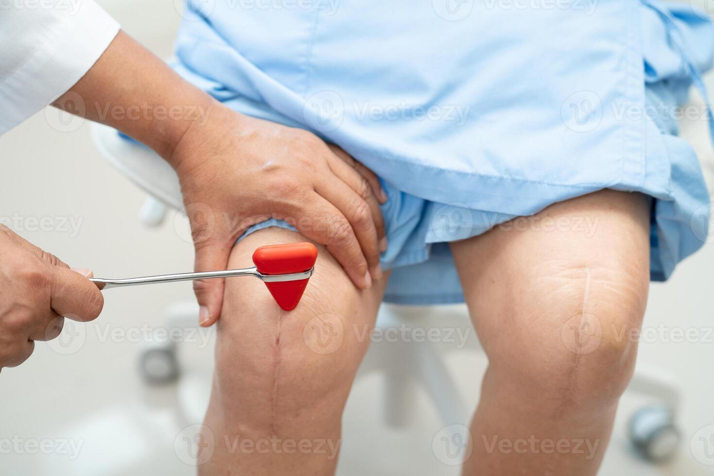 Asian doctor knock on knee reflex nerve for check and treatment senior patient in hospital. photo