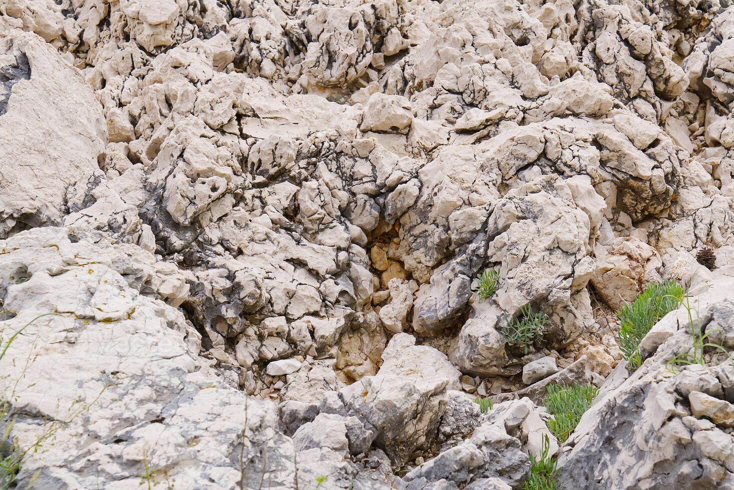 The image presents a close-up view of a weathered rock face characterized by cracks and ledges, showcasing its rough texture and natural beauty from a low angle perspective. photo