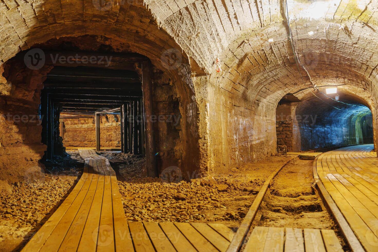 Venture into the depths of an old abandoned mine tunnel, where shadows dance along the wooden walkway and rusty tracks evoke a sense of mystery and exploration in this long-forgotten place. photo