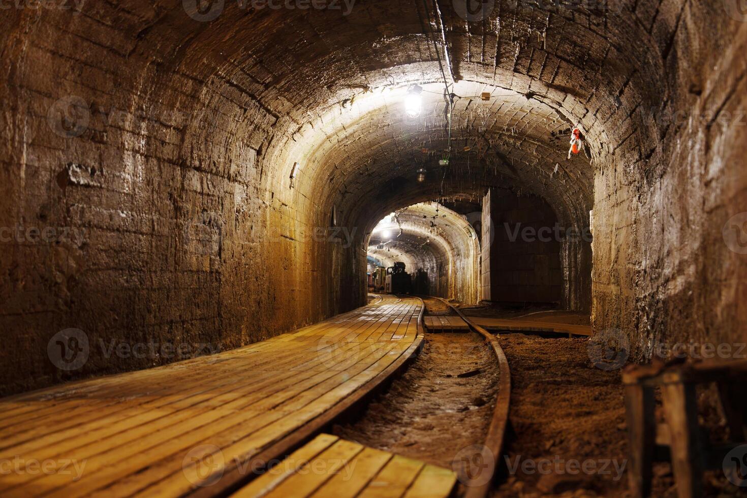 The rusted tracks lead into a deep mountain tunnel, remnants of an era when miners sought precious minerals. This abandoned mine stands as a testament to human ingenuity and determination. photo