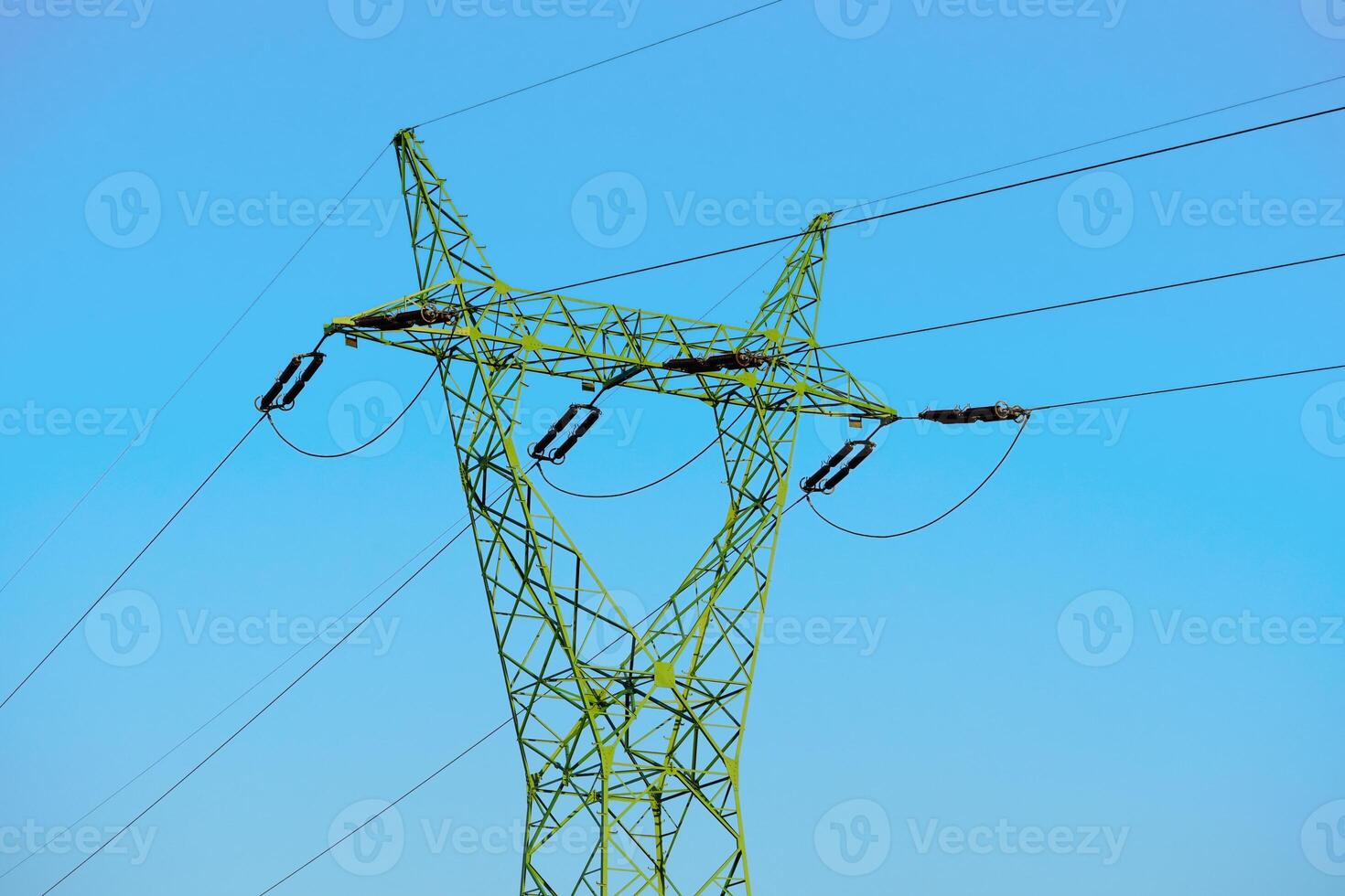 A green electricity pylon rises against a clear blue sky, symbolizing modern energy infrastructure. Its lattice design showcases engineering advancements for efficient power transmission. photo