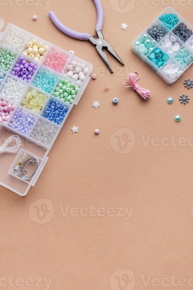 Crafting with colorful beads on a flat workspace with tools and containers in bright daylight photo
