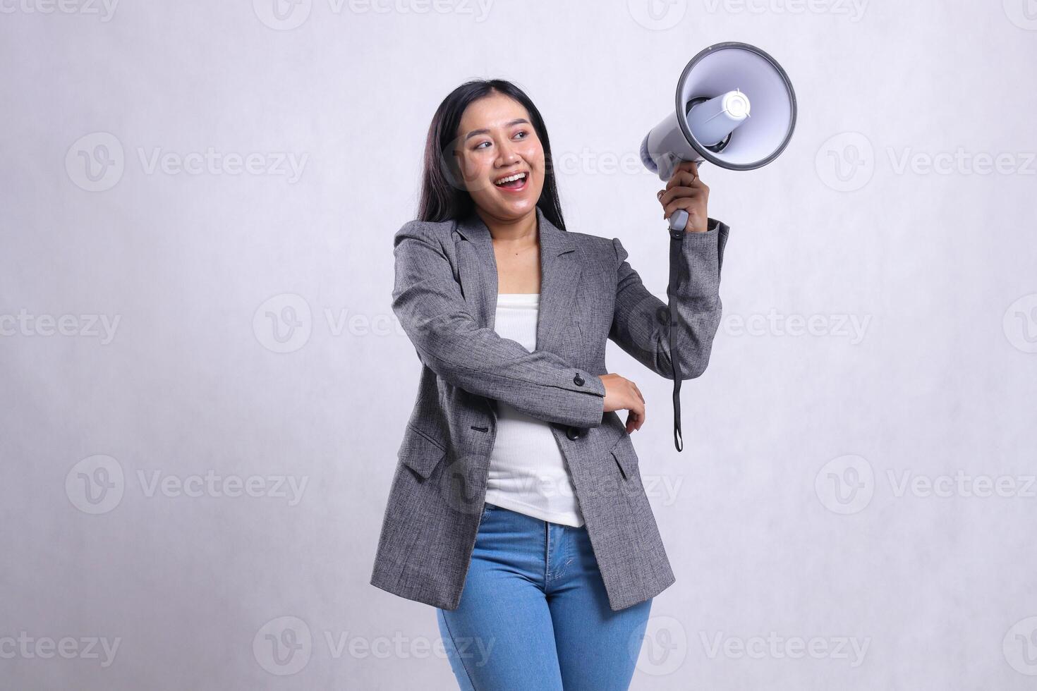 beautiful office girl asia screaming happy candid hugging holding megaphone loudspeaker wearing grey suit isolated on white background. for fashion, lifestyle, advertising, broadcast, shopping content photo