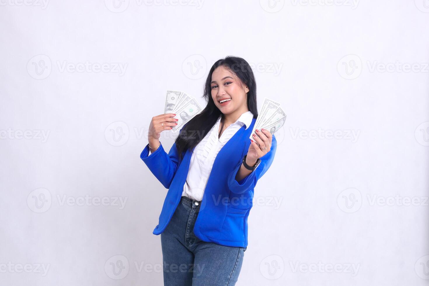 beautiful mature office woman wearing a blue formal suit standing cheerfully to the camera holding dollar bills to the right and left in front of a white background isolation. for transaction photo