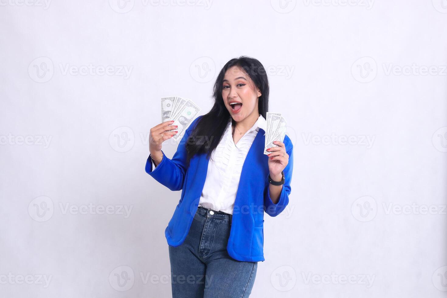 beautiful adult office girl wearing blue formal suit standing cheerfully to the camera holding dollar bills to the right and left isolated on white background. for transaction, finance, business photo